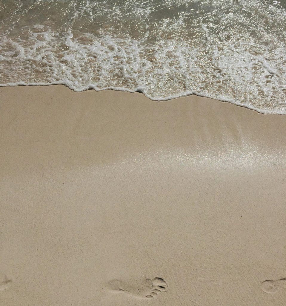 Serene beach scene with footprints in the sand and gentle ocean waves in Dominican Republic.